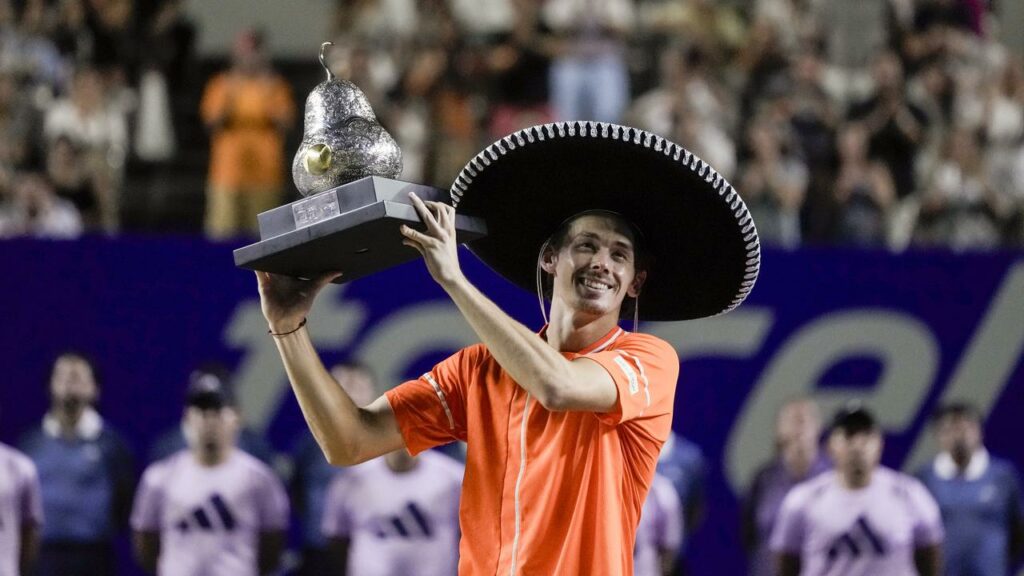 Alex de Minaur holds the trophy aloft after his second successive Mexican Open title triumph.
