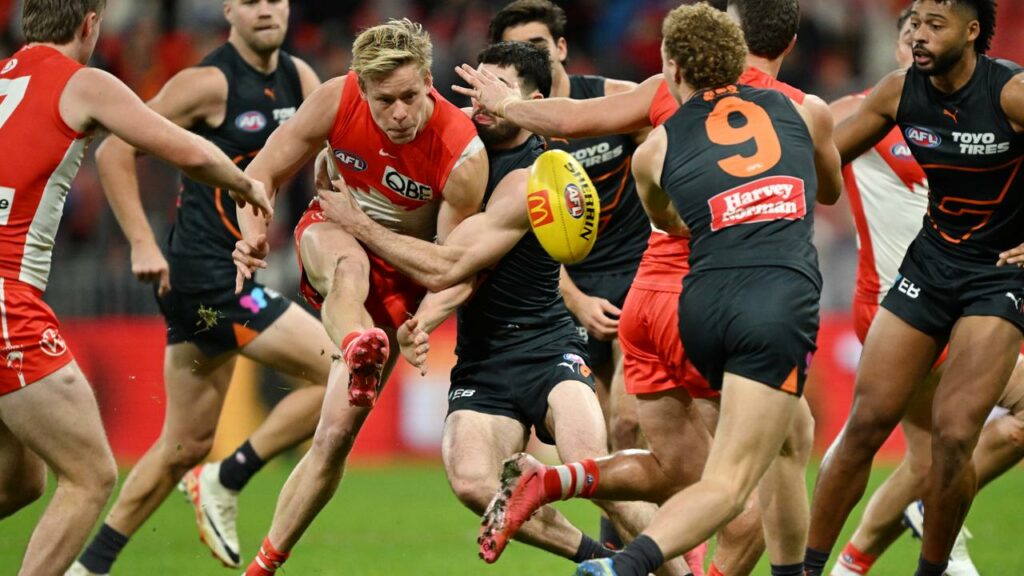 Sydney’s Isaac Heeney (centre) managed to get a kick away despite close attention from the Giants.