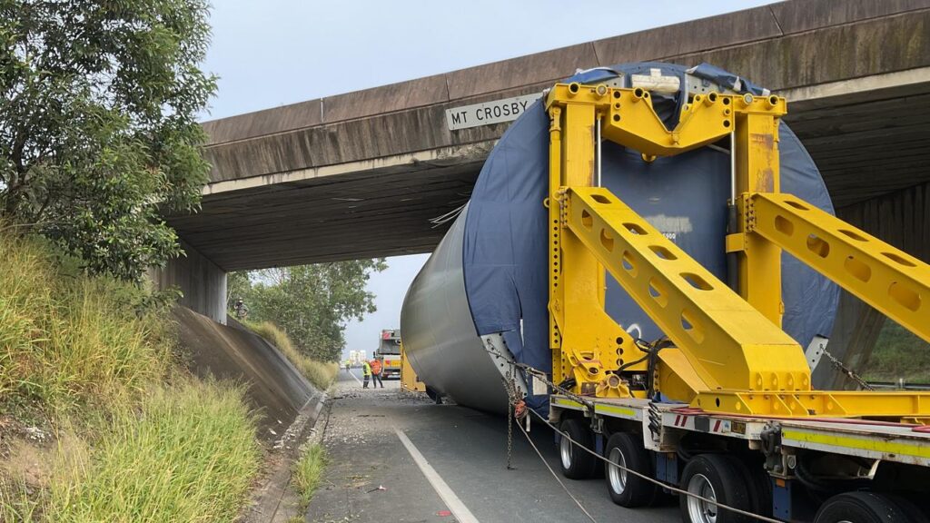 A truck carrying a wind turbine tower got stuck under a major highway overpass in Queensland.