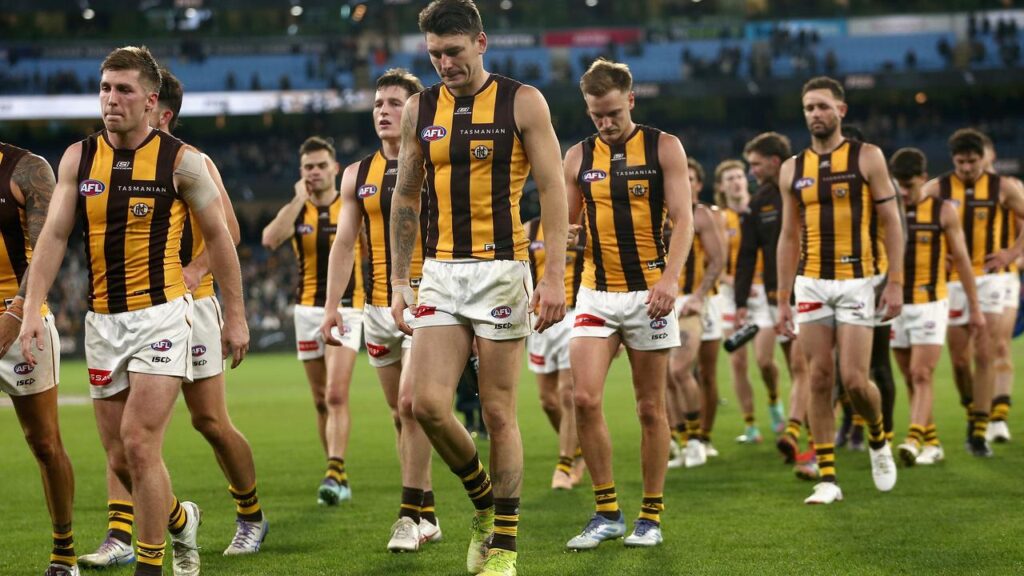 Defeated Hawthorn Hawks players walk off the pitch after being second best to Collingwood Magpies.