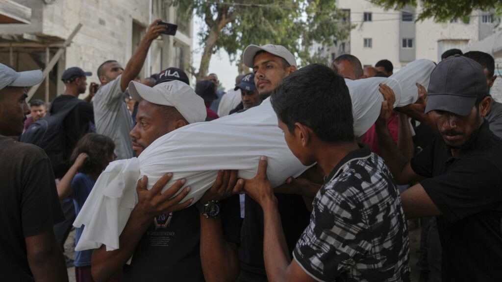 Palestinians in Gaza City carry the body of a person killed while trying to reach aid trucks.

