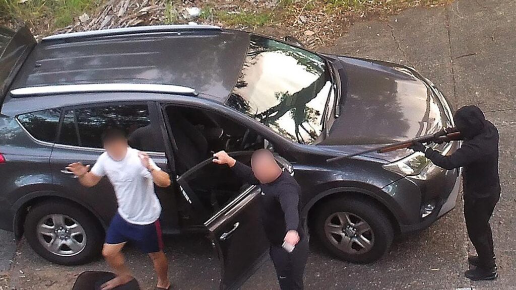 A man had his hands up exiting a car with a masked offender pointing a gun at him.