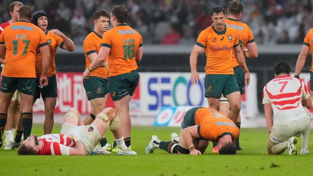Relieved Australian players celebrate their gritty win over the Brave Blossoms in Tokyo.