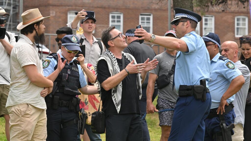 Police speak to a pro-Palestine protester who is heckled at the Bondi Pavilion on Sunday.
