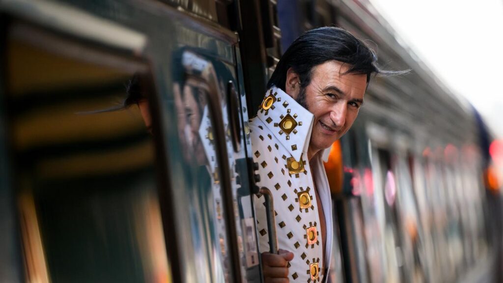 A fan dressed as Elvis Presley waits for the departure of the Elvis Express train.
