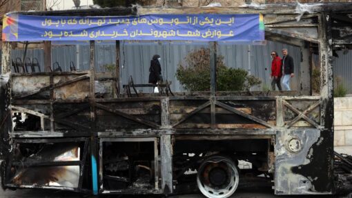 Iranians pass wreckage of bus in Tehran