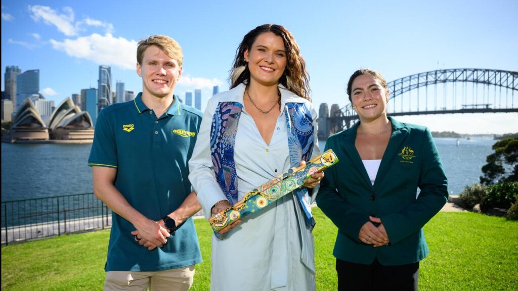 Designer Chern’ee Sutton shows the King’s Baton with athletes Timothy Hodge and Georgia Godwin.
