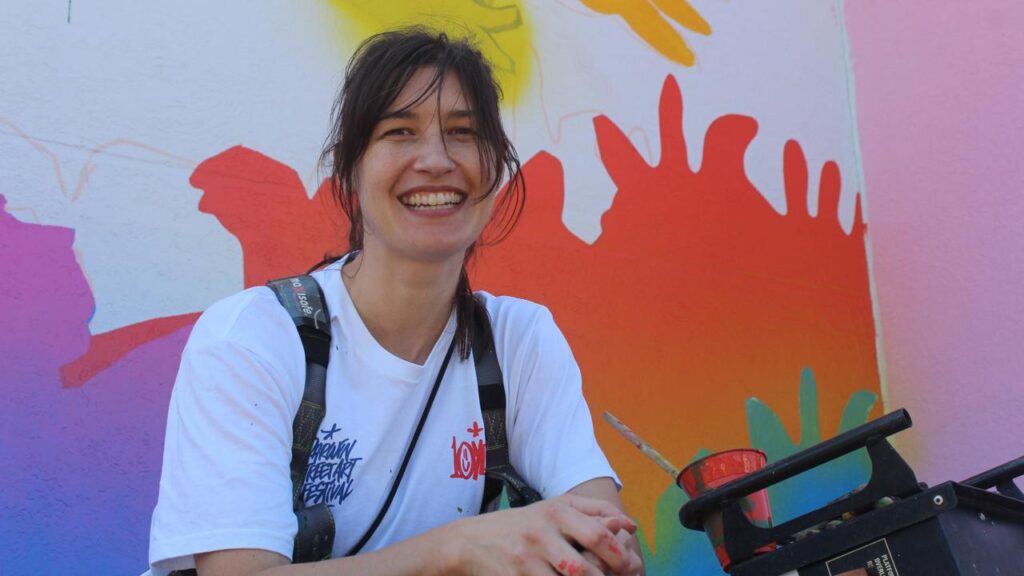 Muralist George Rose paints free-hand, reshaping her design as she works.
