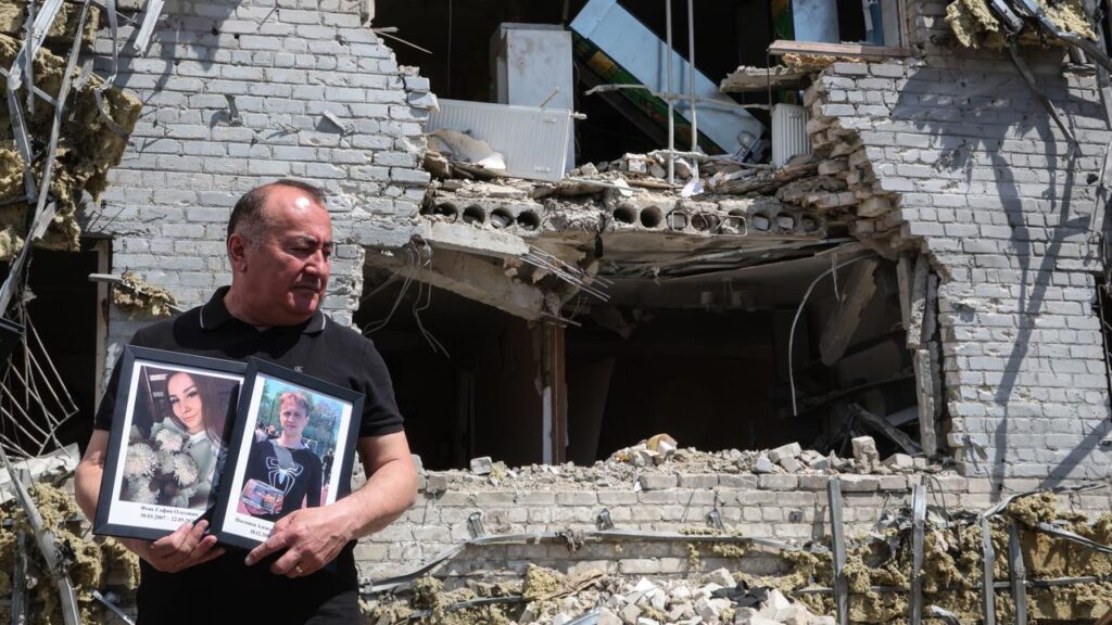 A teacher with the portraits of students who died when the dormitory came under attack.
