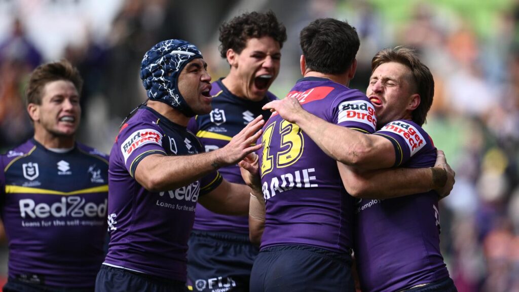 Melbourne players celebrate one of Cameron Munster’s two tries in a big win over Wests Tigers. 
