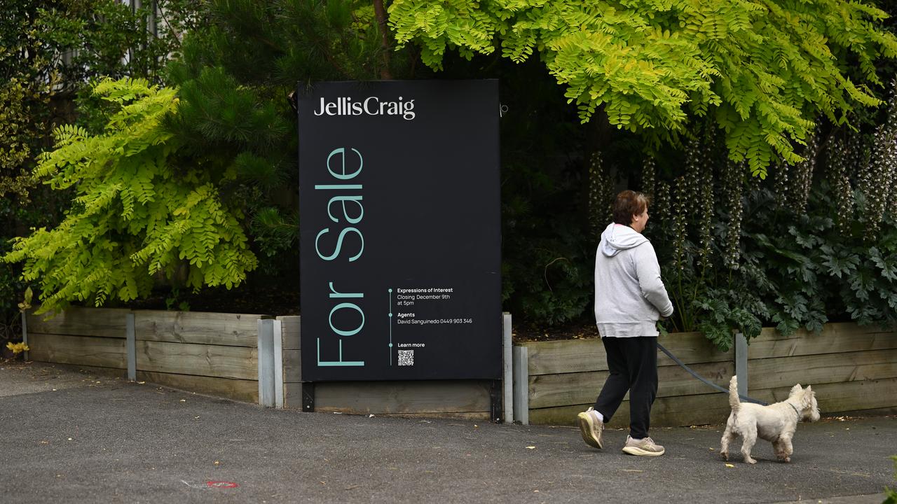 A person walking a dog past a for sale sign (file image)