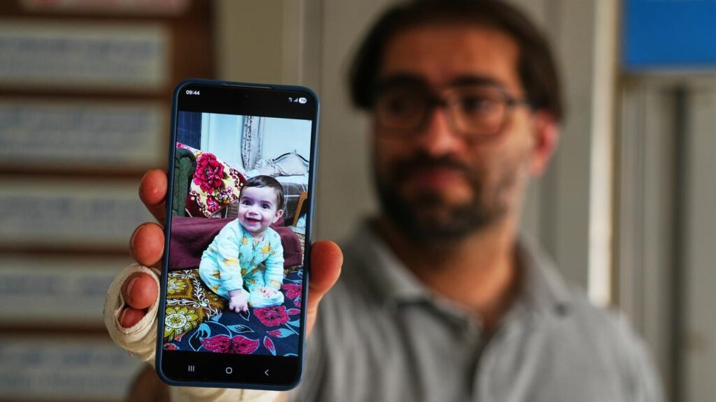 Fahd Abu Haikal holds up a photo of his baby boy Sam, who was killed by Israeli gunfire.
