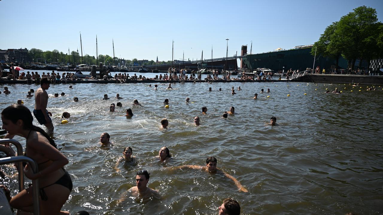 People swim in a canal during warm weather in Amsterdam, Netherlands