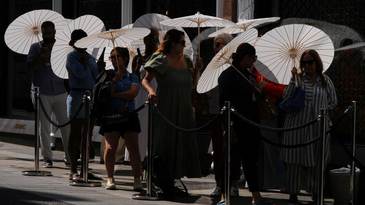People use parasols as they queue outside a shop in London