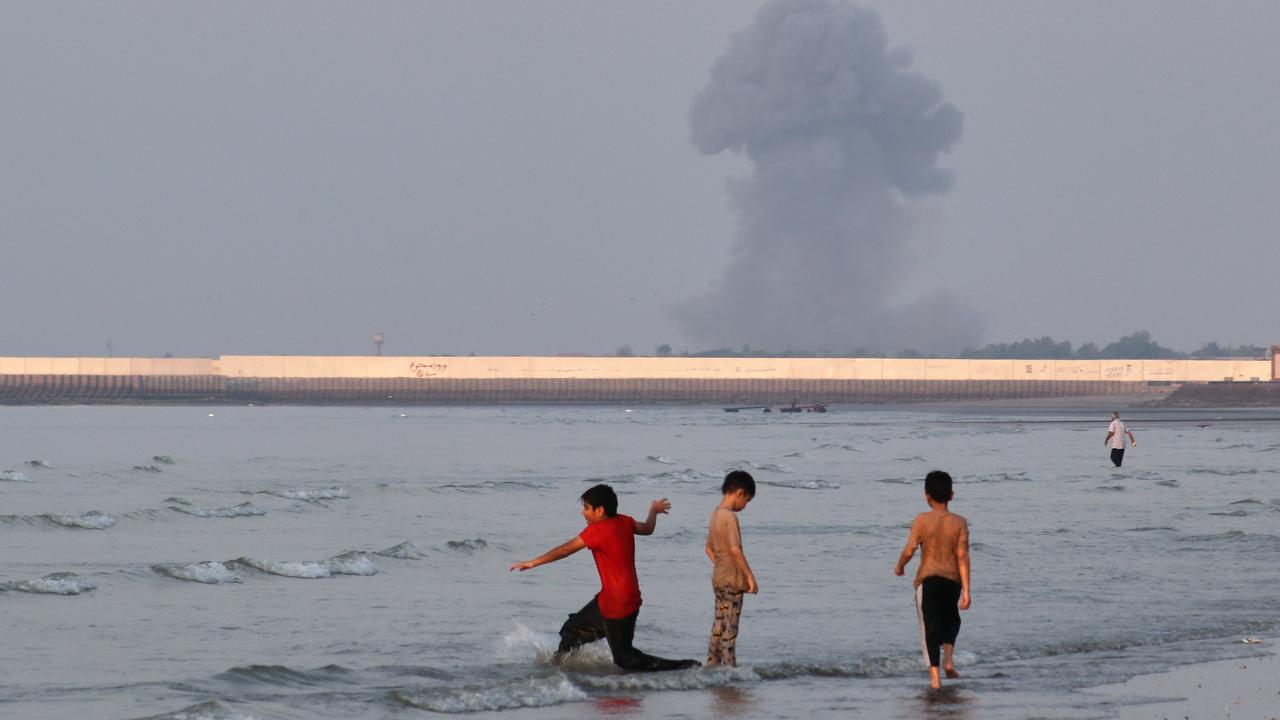 The Strait of Hormuz as a plume of smoke rises from an explosion