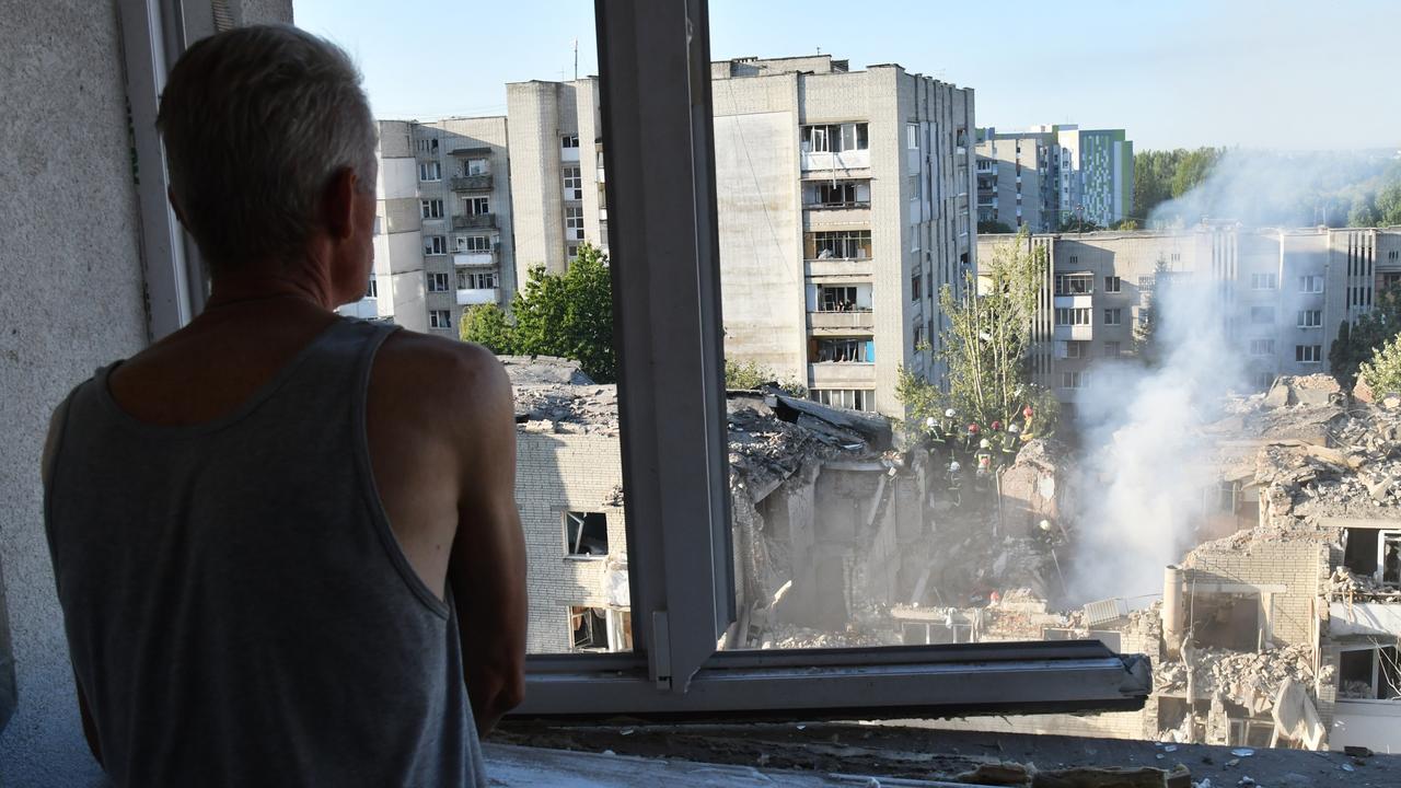 A man watches as rescuers clear rubble after a Russian attack in Lviv