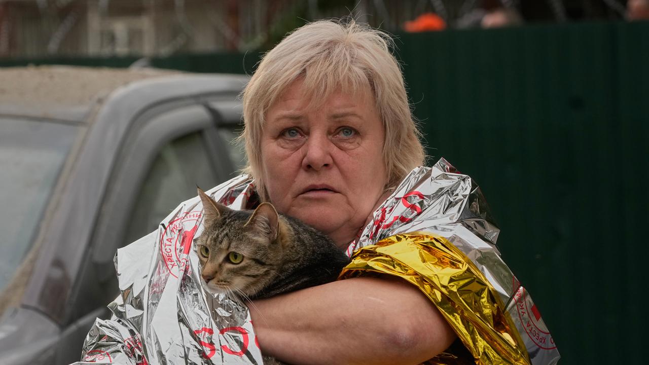 A woman carries her cat out of an apartment building in Kyiv