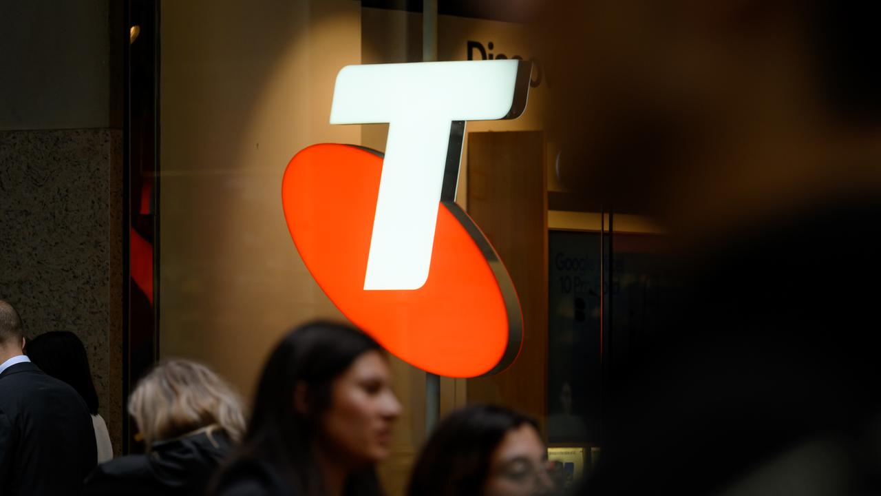 People walking past Telstra signage