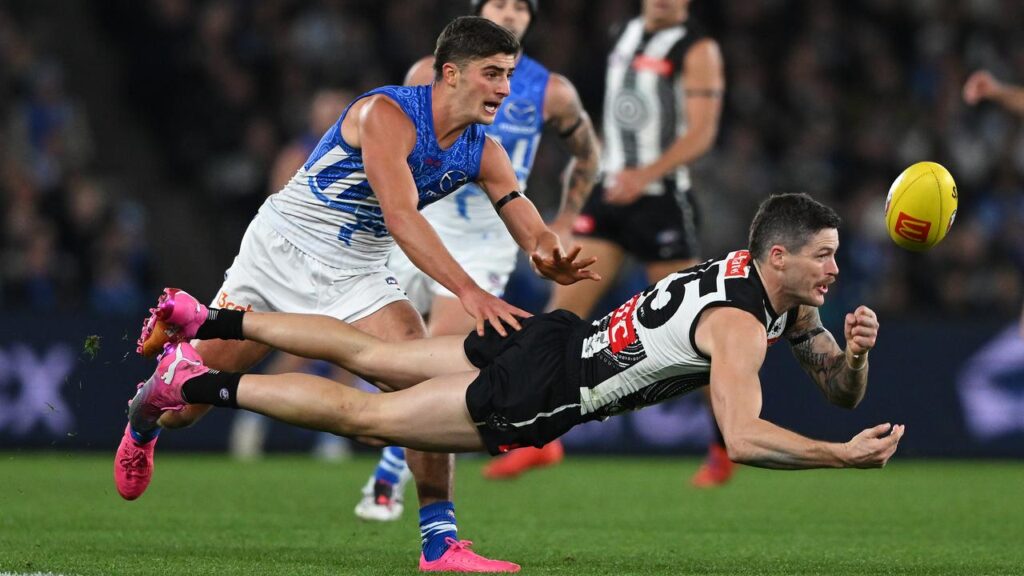 Collingwood’s Jack Crisp fires out a handpass despite pressure from the Kangaroos’ Harry Sheezel. 
