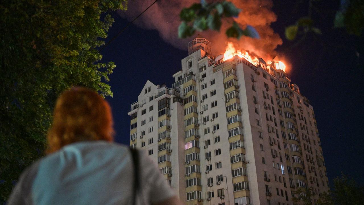 A woman looks at an apartment building burning in Kyiv