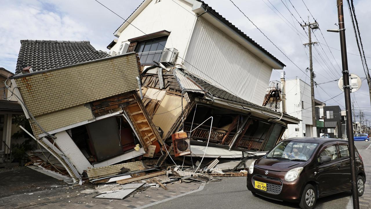 A vehicle passes by collapsed houses after an earthquake in Yatsushiro