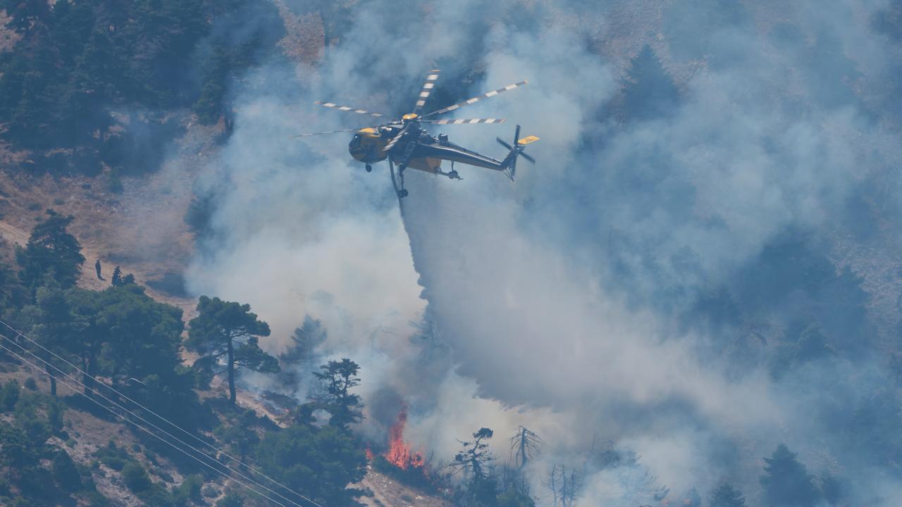A helicopter drops water over a wildfire near Athens, Greece