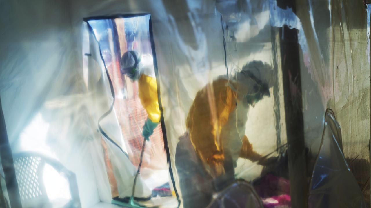 Health workers wearing protective suits tend to an Ebola victim