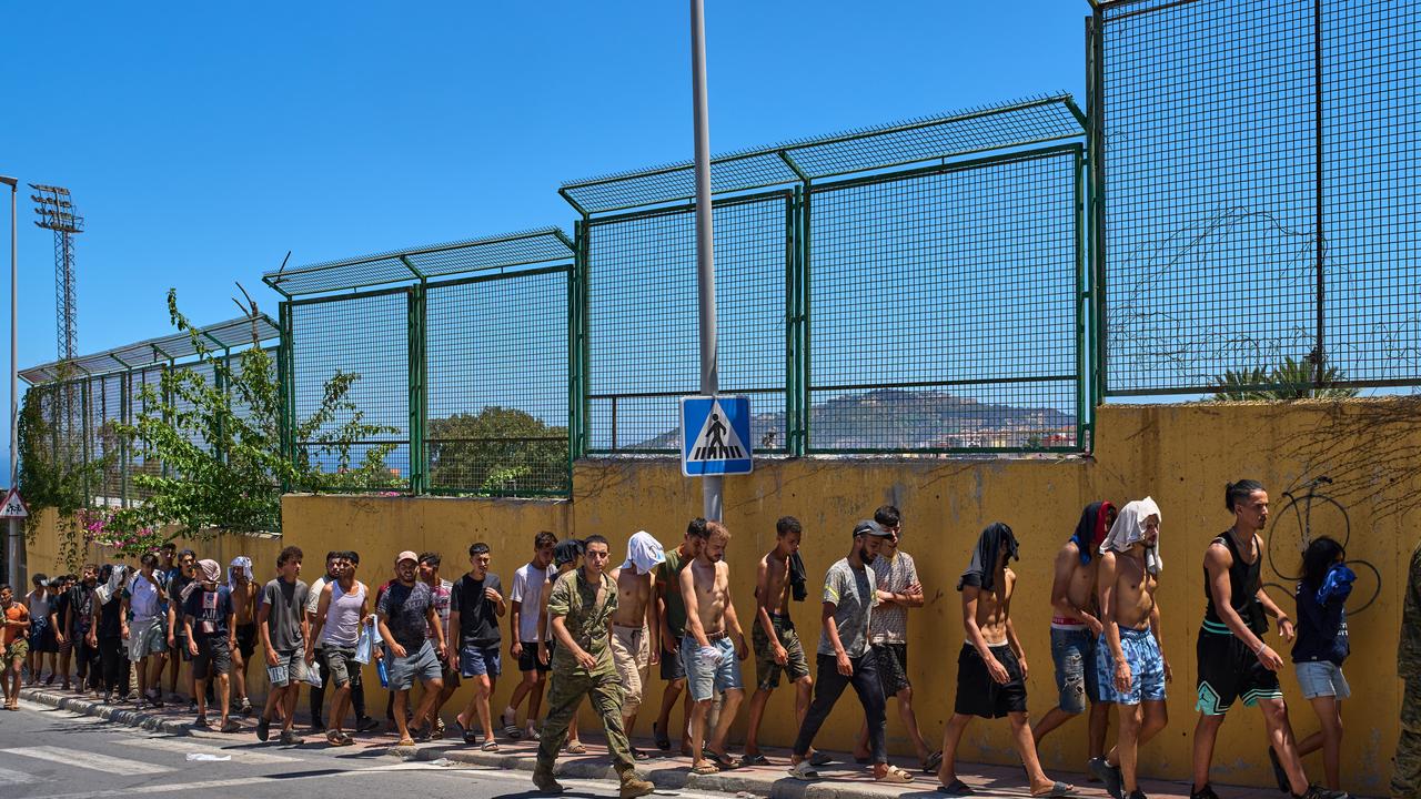 Migrants who crossed into Spain are escorted by Spanish soldiers