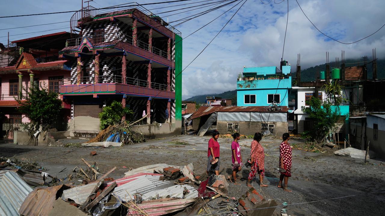 People walk past damage in the aftermath of flash floods in Nepal