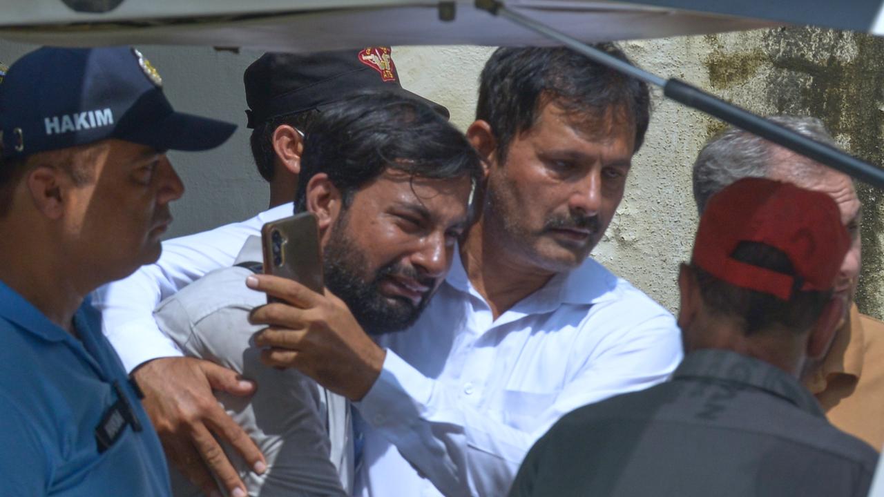 A father is comforted as his child's coffin is carried ouside