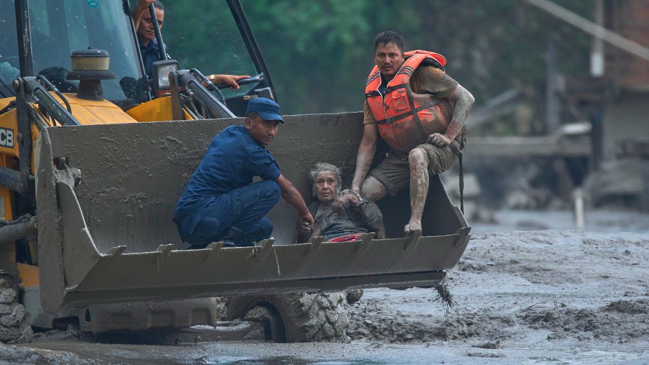 Rescuers use an earthmover to save a woman from floods.