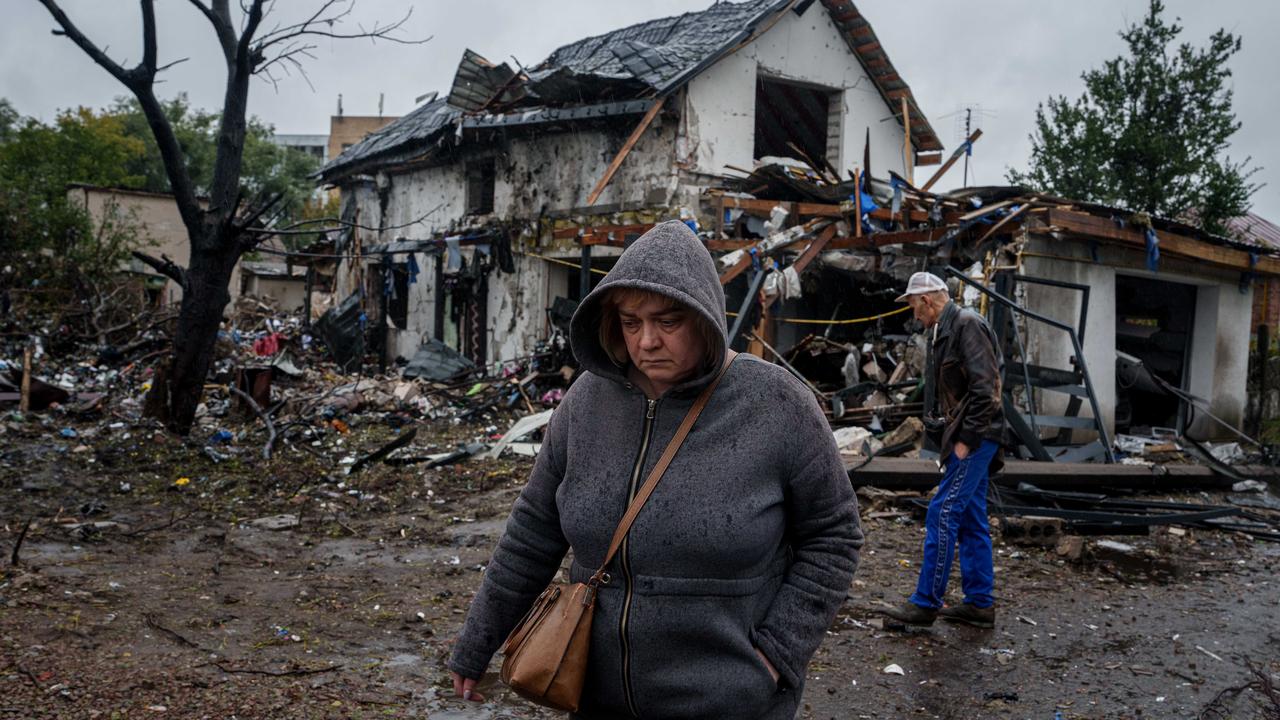 A woman walks in front of a damaged house in Kyiv, Ukraine