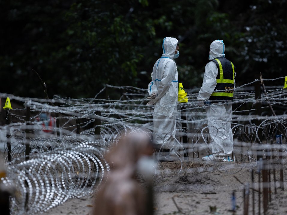 Barbed and razor wire cover the grave site of unidentified victims