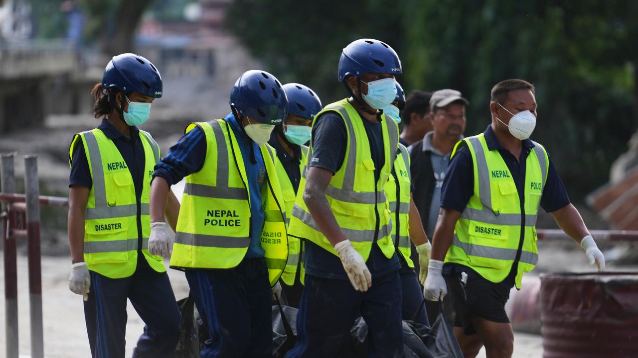 Nepal police personnel carry the body of a flash flood victim