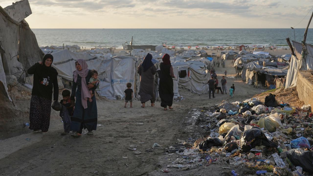 Women walk along a street surrounded by tents