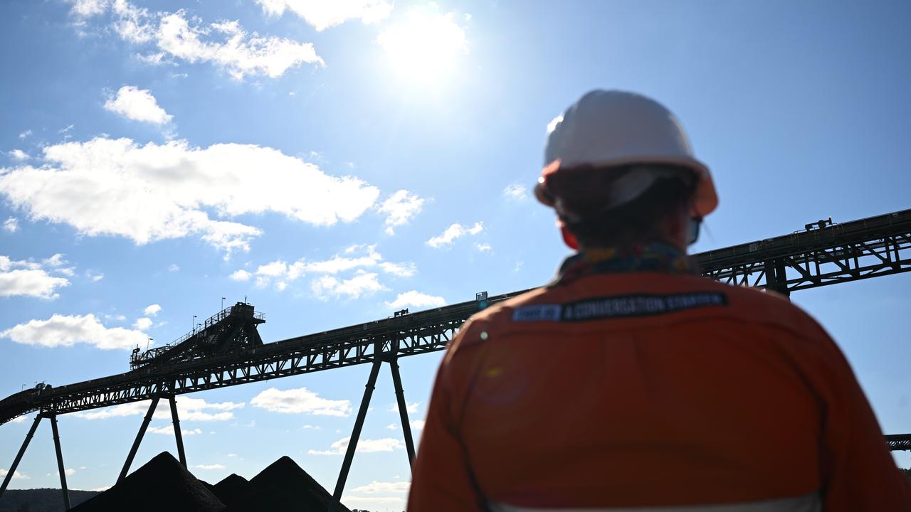 A worker looks at a conveyor belt delivering coal