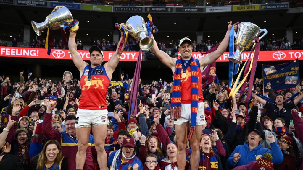 Dayne Zorko and Josh Dunkley celebrate Brisbane’s premiership three-peat with Lions fans.
