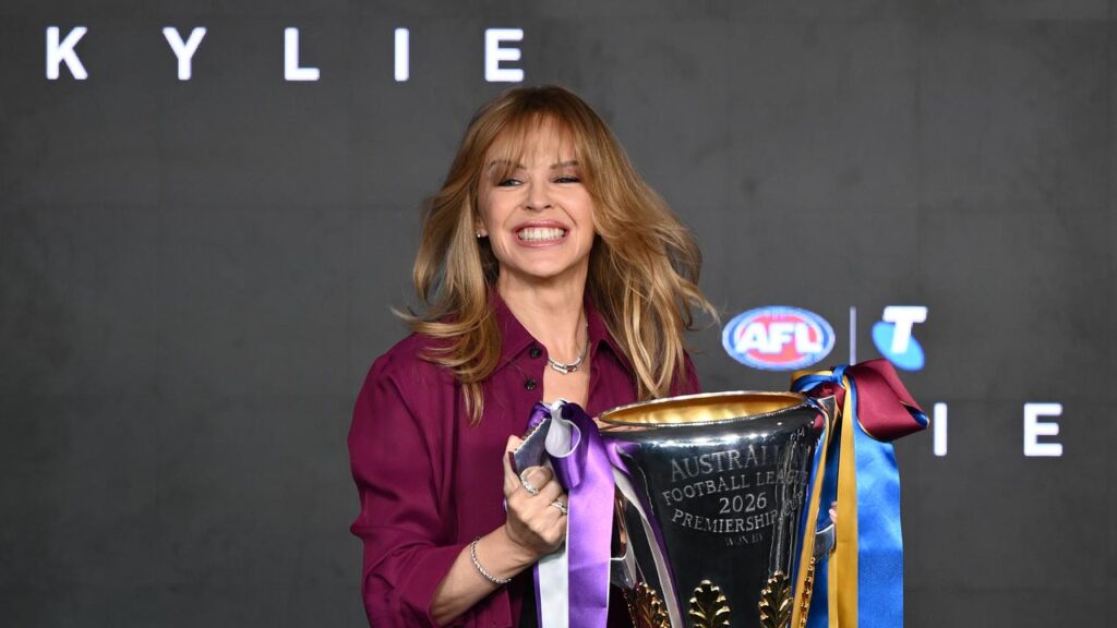 Superstar Kylie Minogue holds the premiership cup before finally performing at an AFL grand final. 
