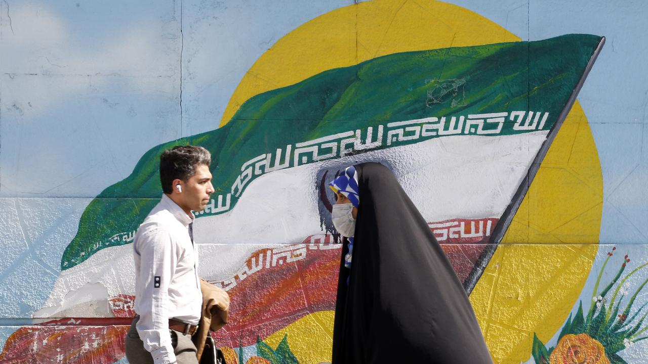 Iranians walk past painting of Iran's flag in downtown Tehran