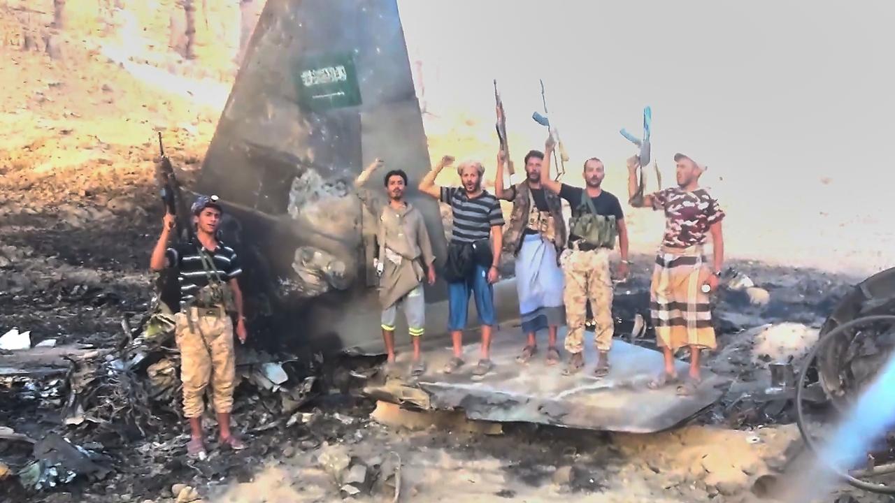 Houthi fighters posing with the wreckage of a Saudi F-15 fighter jet