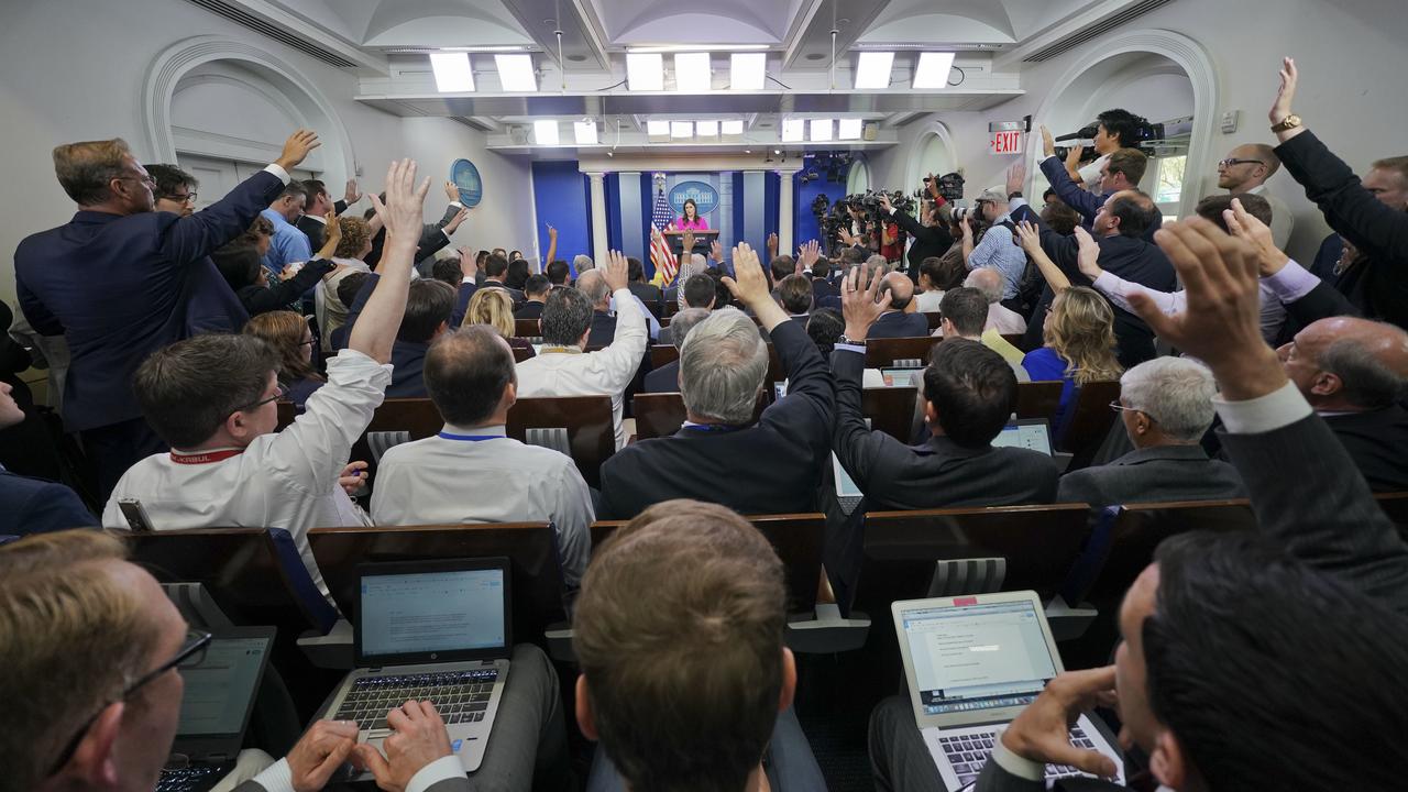 Journalists raise their hands in the White House press room