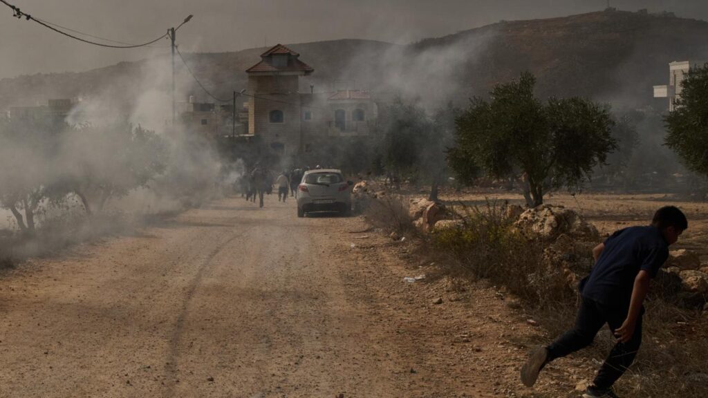 Palestinians run from tear gas fired by Israeli forces after an attack in a West Bank village.
