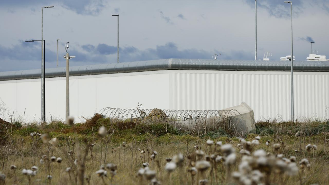 prison wall, with barbed wire in foreground